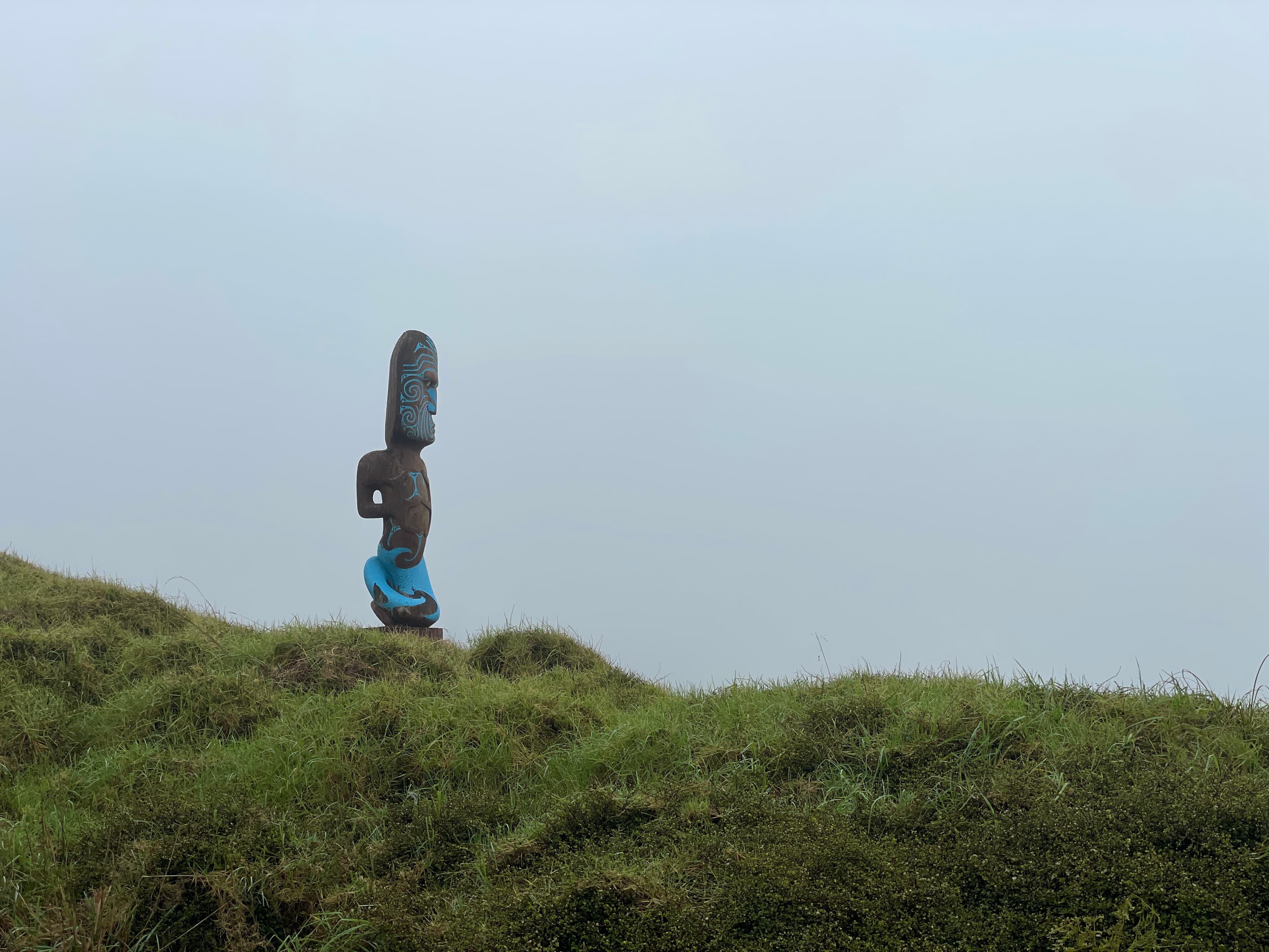 Carved figure standing on a grassy ridge