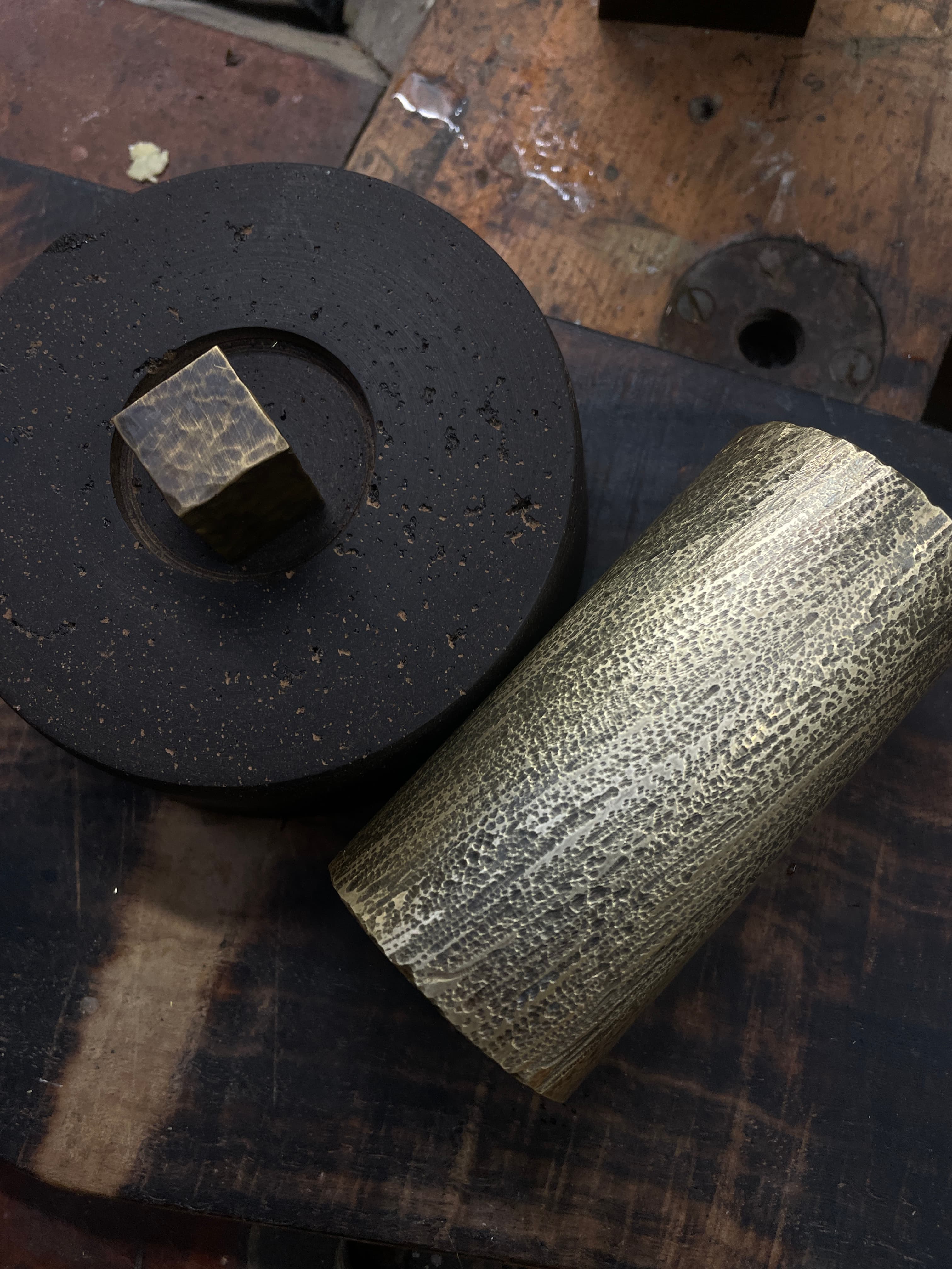 Black and hand-finished brass forms arranged on a workshop bench
