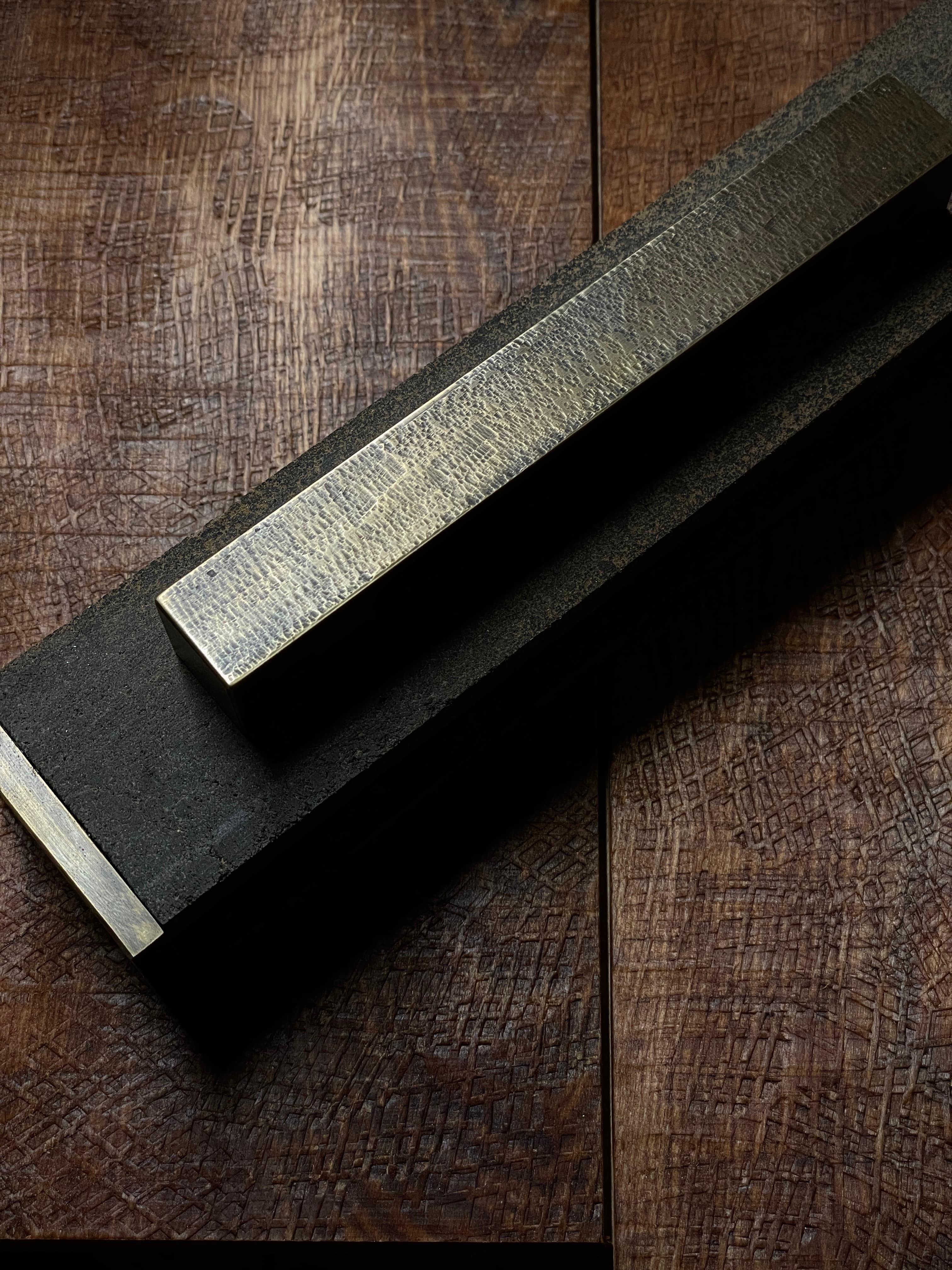 Hand-finished brass bar resting across black material forms