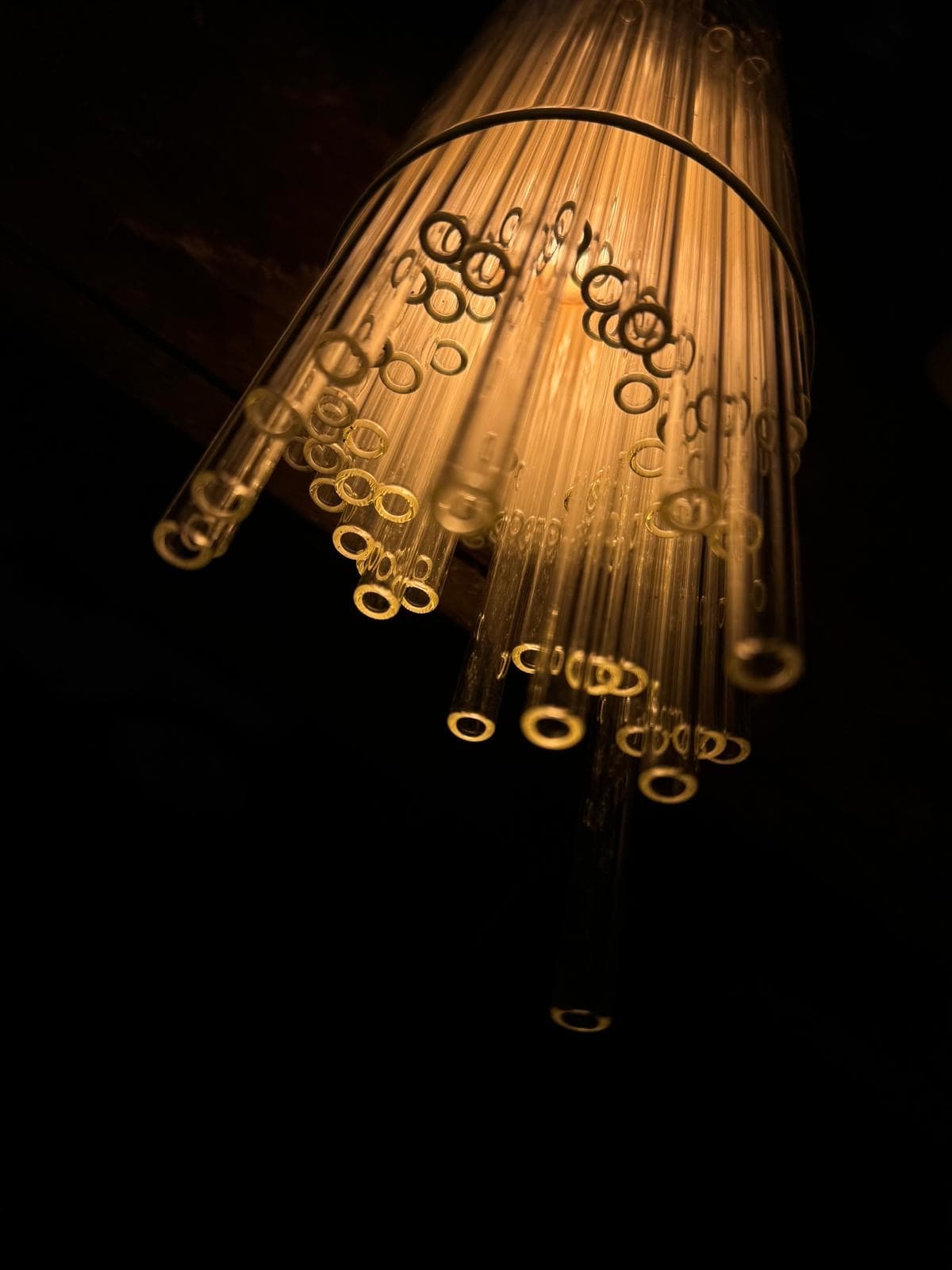 Ends of illuminated glass straws gathered into a suspended light study