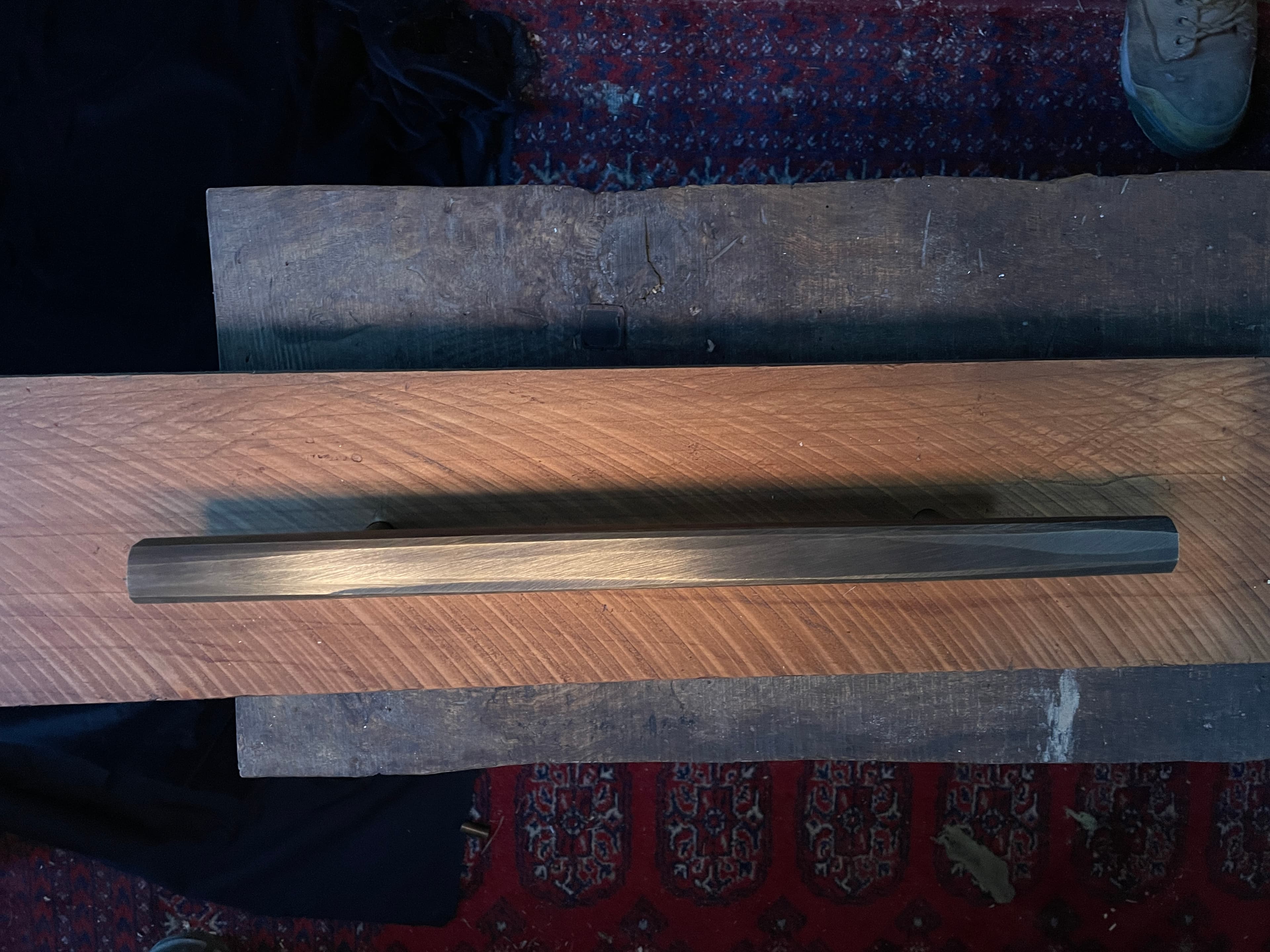 Long dark metal handle resting across carved timber workbenches