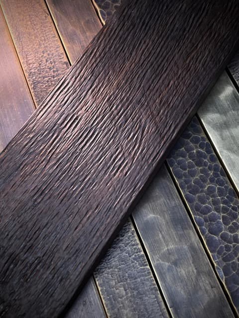 Dark textured timber laid across patinated metal strips